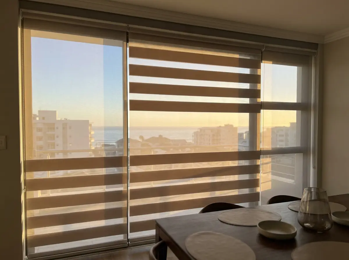 Day/night banded blind over a dining room window, warm late-afternoon light through the bands